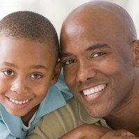 Man and young boy embracing and smiling Man and young boy embracing and smiling