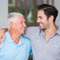 Smiling father and son with arm around wile standing at home Smiling father and son with arm around wile standing at home